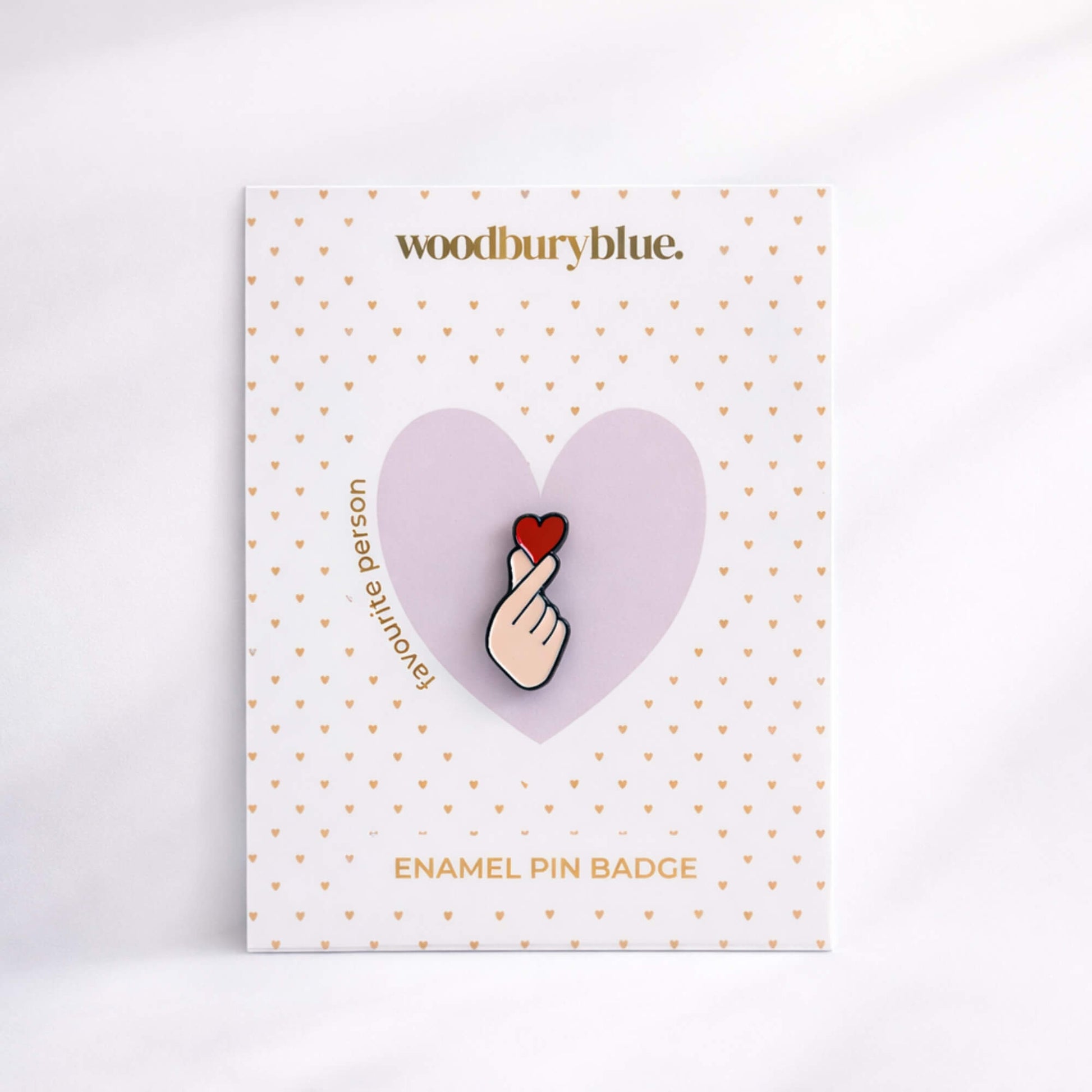 Hand holding heart enamel pin badge on Woodbury Blue backing card, thoughtful Galentine’s or friendship gift