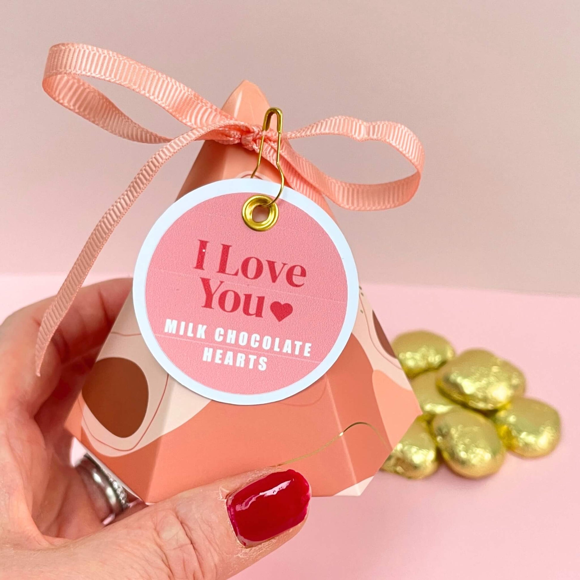 hand holding a pyramid shaped gift box with an I Love You gift tag and milk chocolate hearts