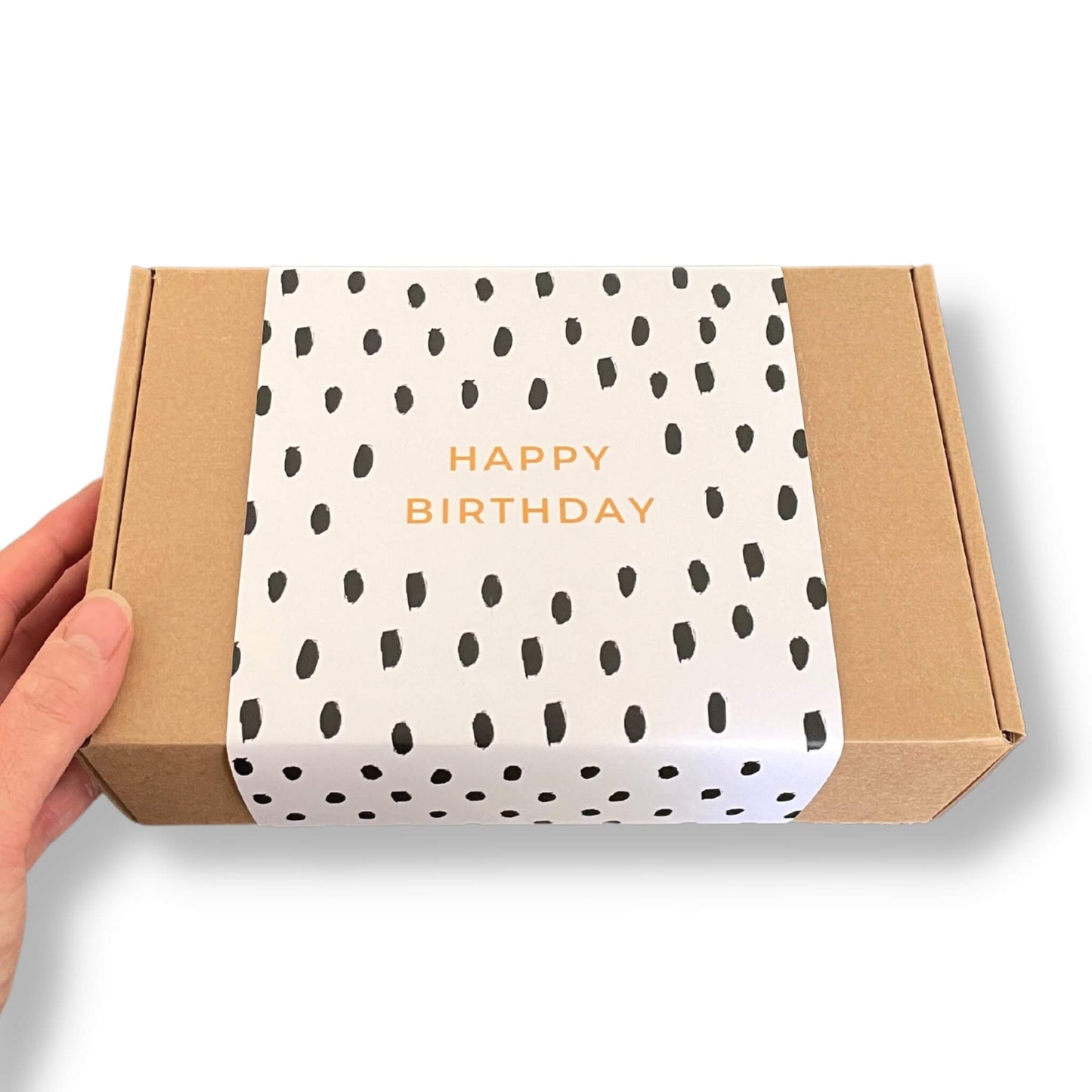 Kraft gift box with a black and white dash pattern and happy birthday in gold text