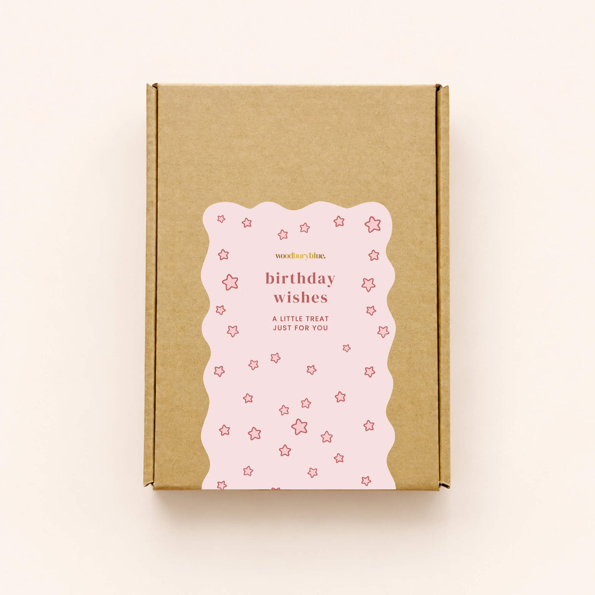 Closed kraft birthday letterbox gift box with a pink star-patterned Woodbury Blue sticker reading Birthday Wishes, A Little Treat Just For You.