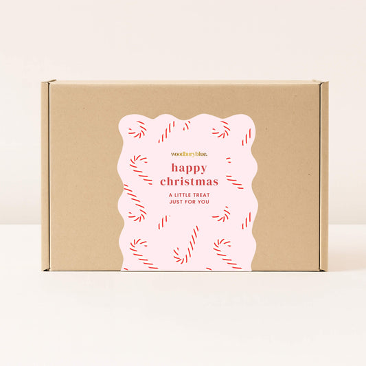 Kraft gift box with pink happy Christmas sticker decorated with red candy canes from Woodbury Blue