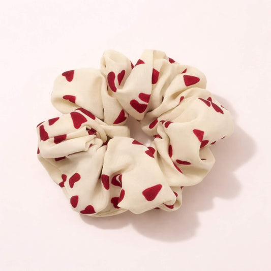 Cream heart patterned scrunchie with red hearts photographed on a neutral background