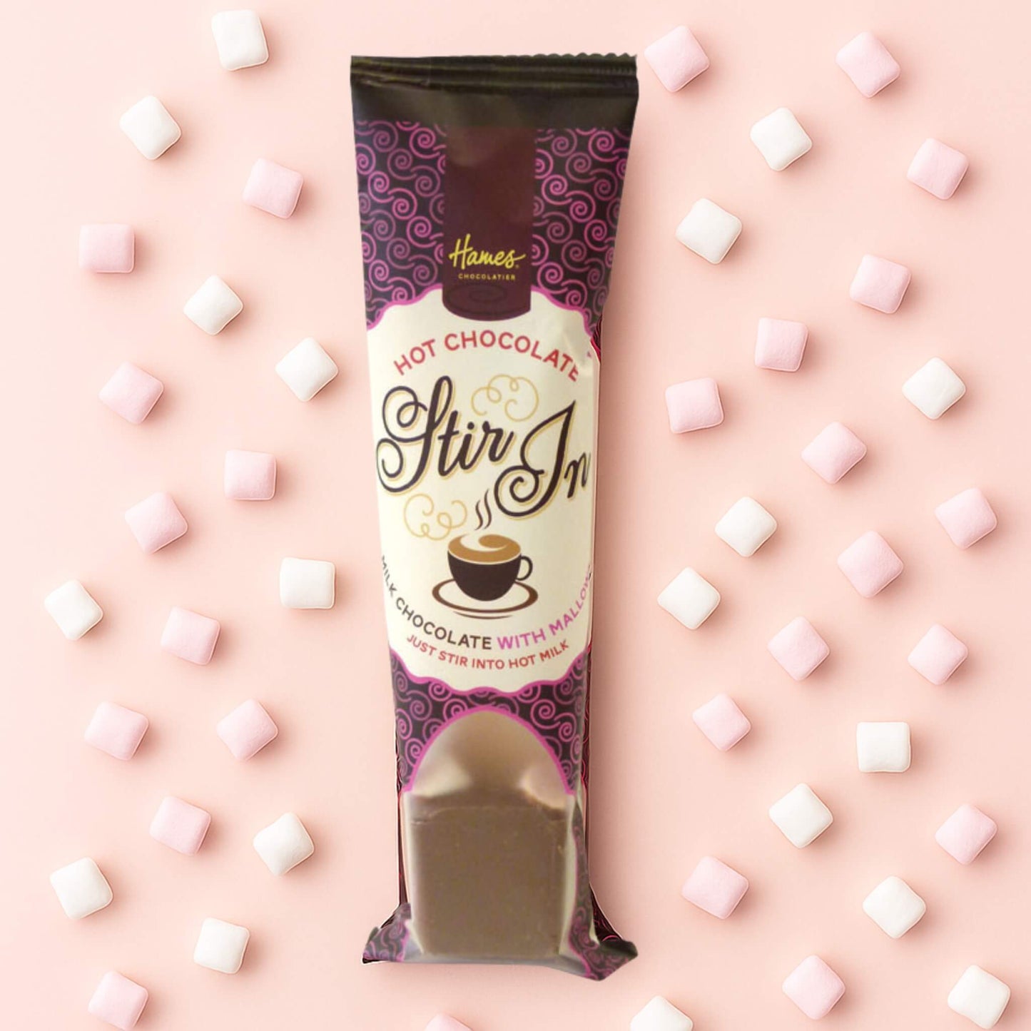 Hot Chocolate Mini Mallow Stirrer by Hames Chocolates on a blush pink background with scattered pink and white mini marshmallows.