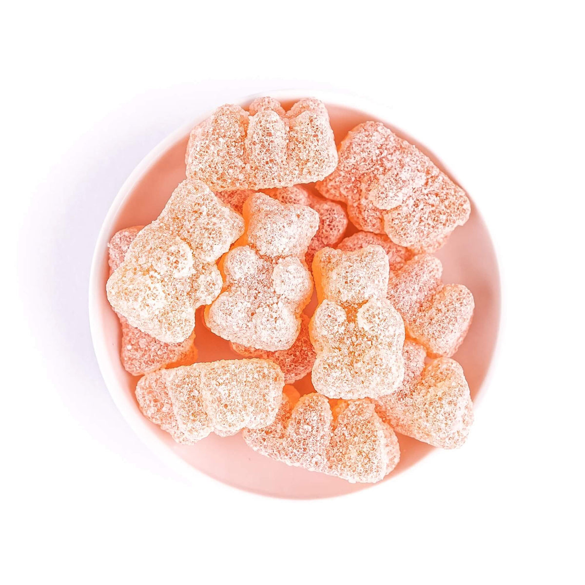 Close-up of orange Italian Spritz gummy bears covered in a sugar coating and arranged in a pale pink bowl.