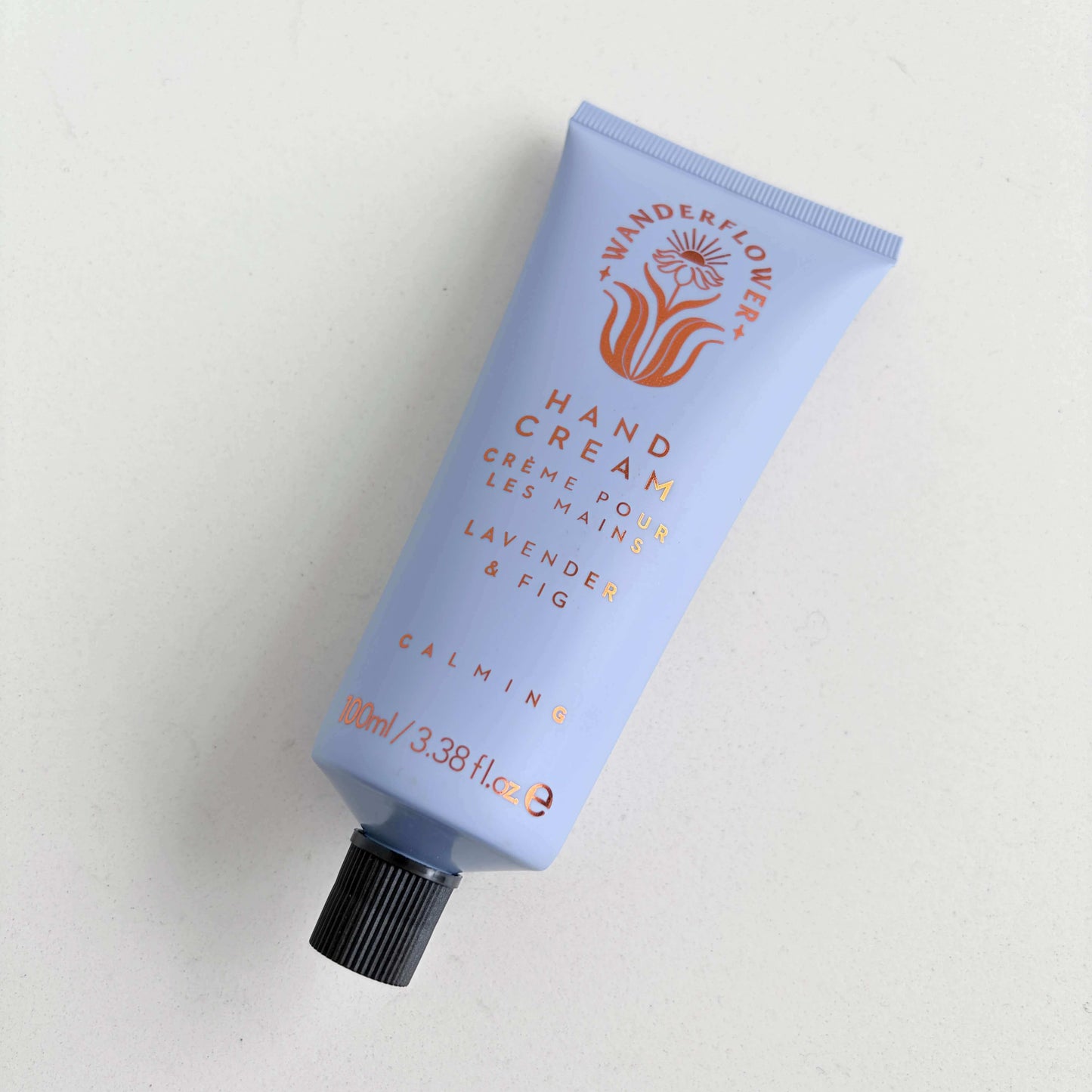 Lavender and fig hand cream tube laid flat on a light background