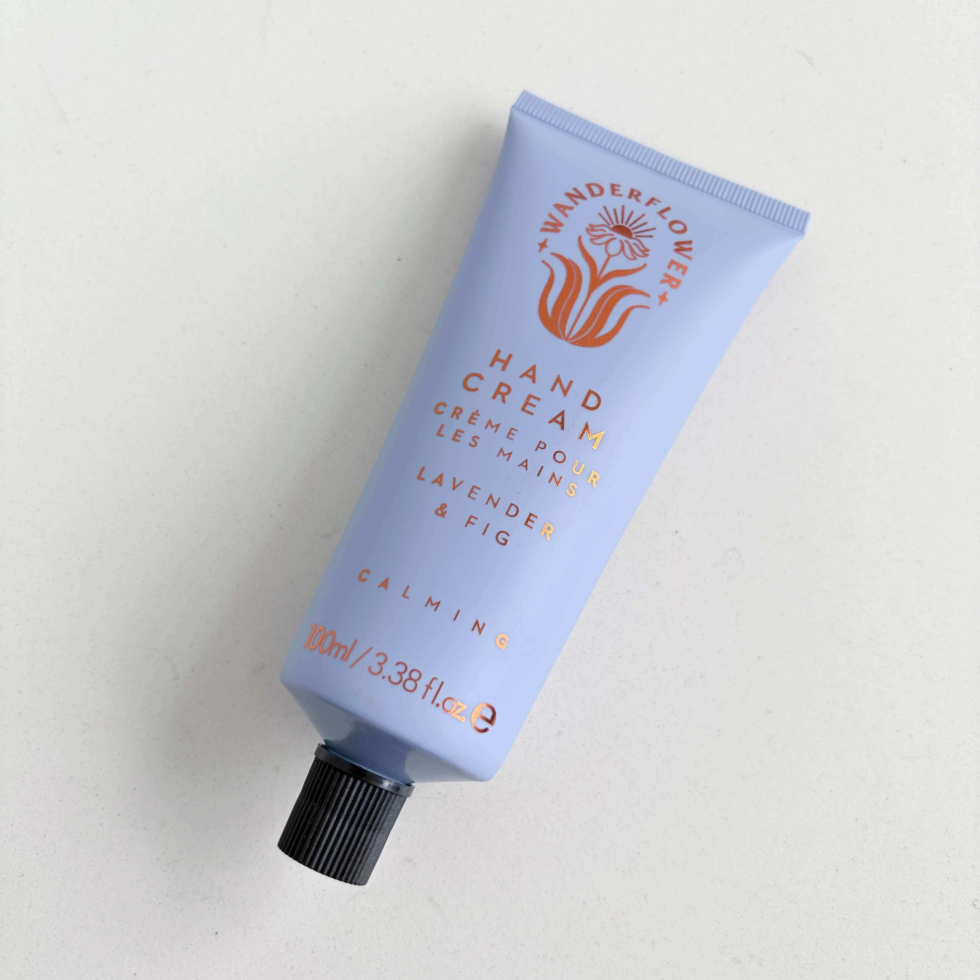 Lavender and fig hand cream tube laid flat on a light background