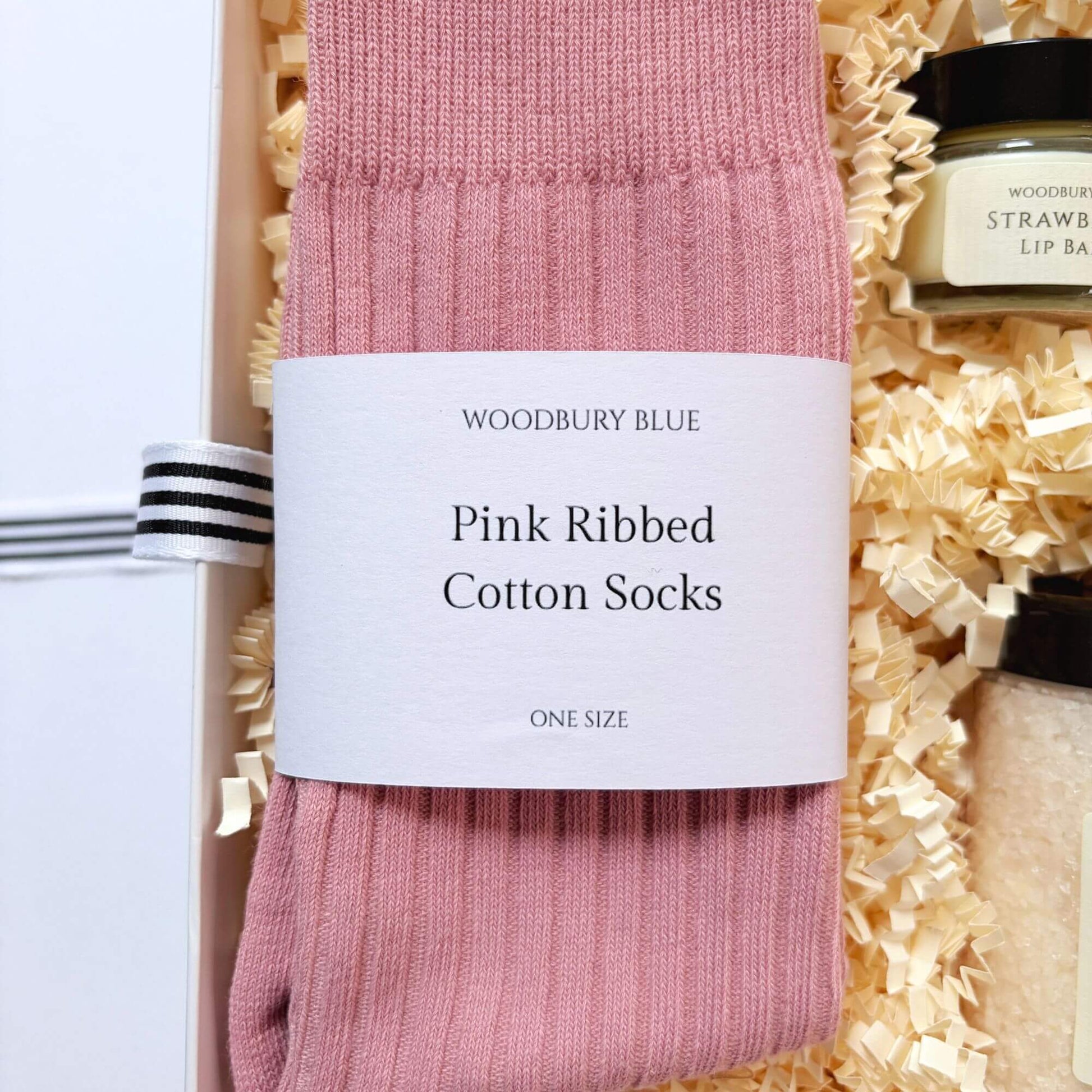 Pink ribbed cotton socks inside a luxury birthday gift box with strawberry lip balm and birthday cake bath salts.