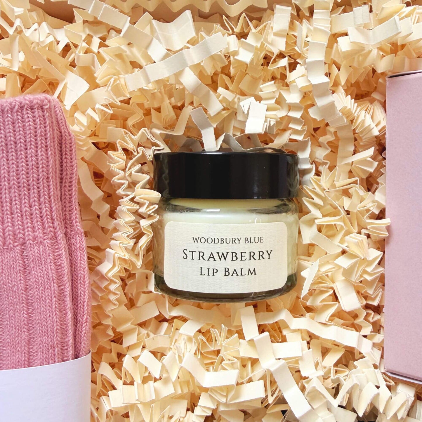 Strawberry lip balm inside a luxury birthday gift box with pink cotton socks and rose bath infusion.