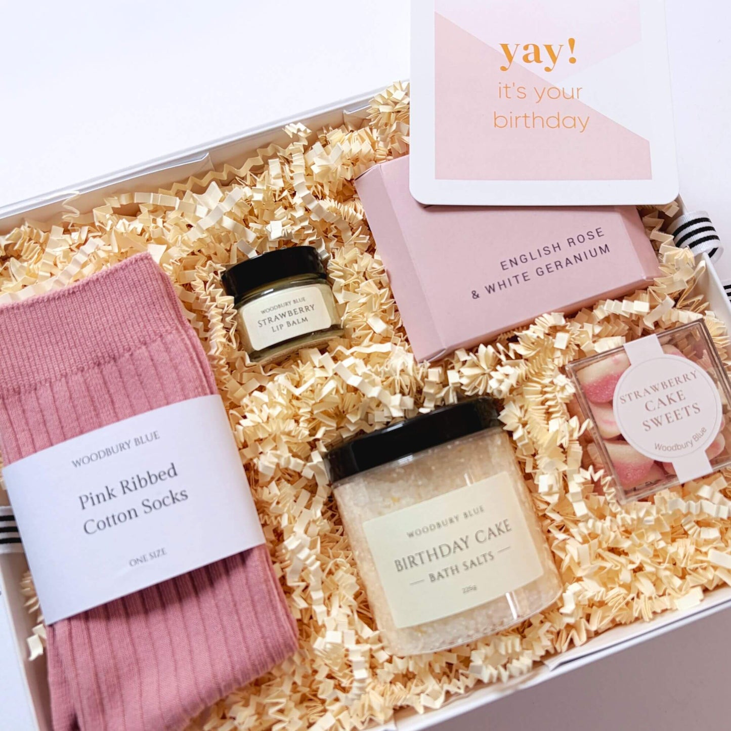 Luxury birthday gift box with pink cotton socks, birthday cake bath salts, strawberry lip balm, strawberry cake sweets, rose bath infusion and birthday card.
