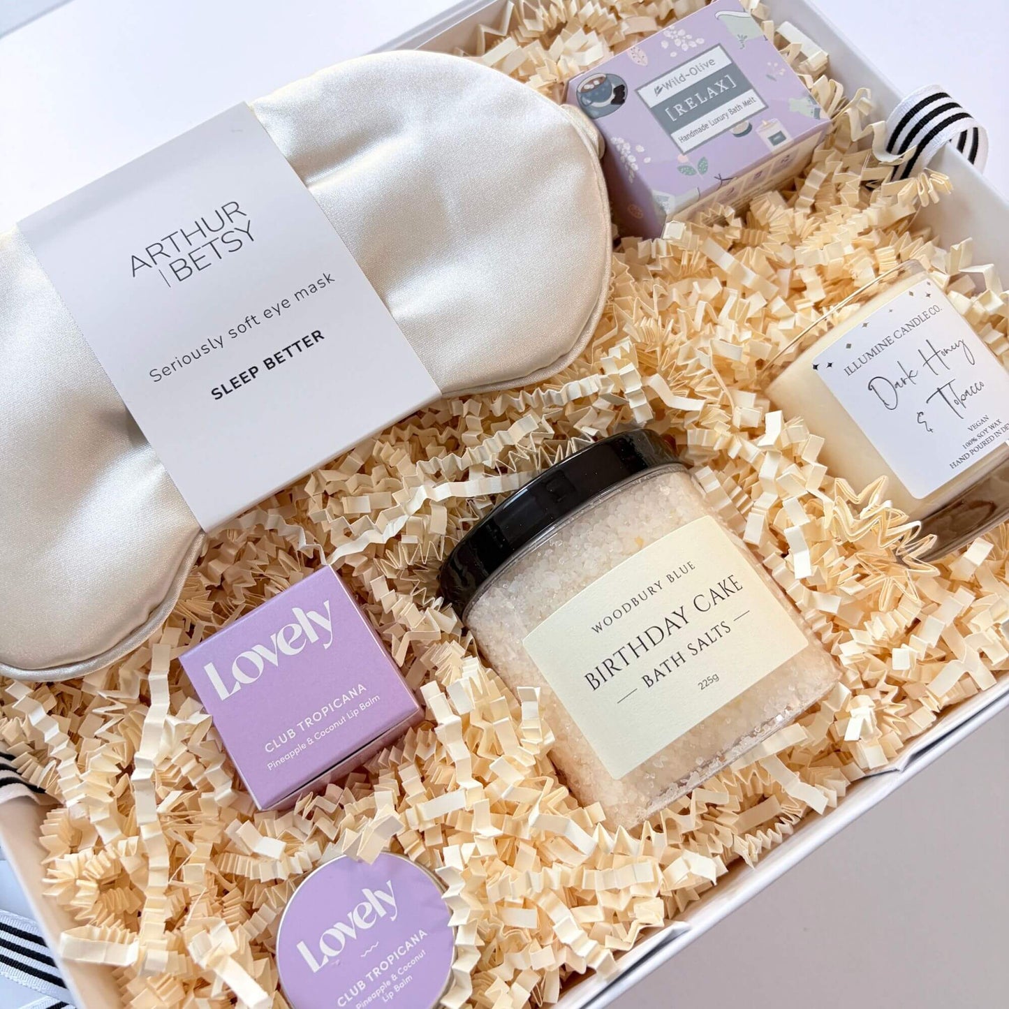 Luxury birthday pamper gift box with silk eye mask, birthday cake bath salts, dark honey candle, pineapple coconut lip balm and lavender bath melt.