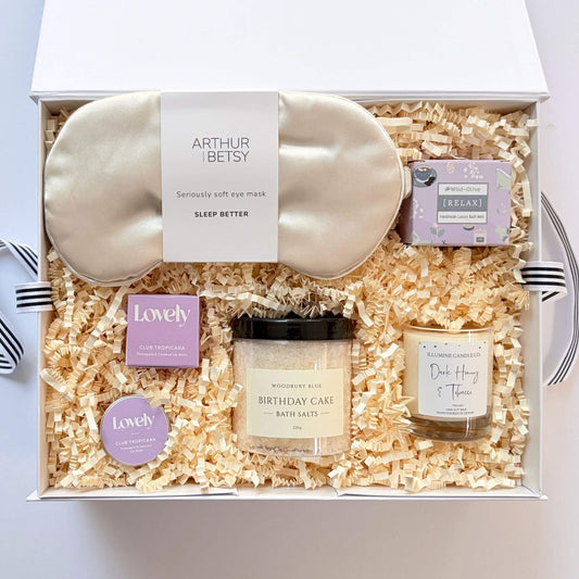 Luxury birthday pamper gift box with silk eye mask, birthday cake bath salts, dark honey candle, pineapple coconut lip balm and lavender bath melt.