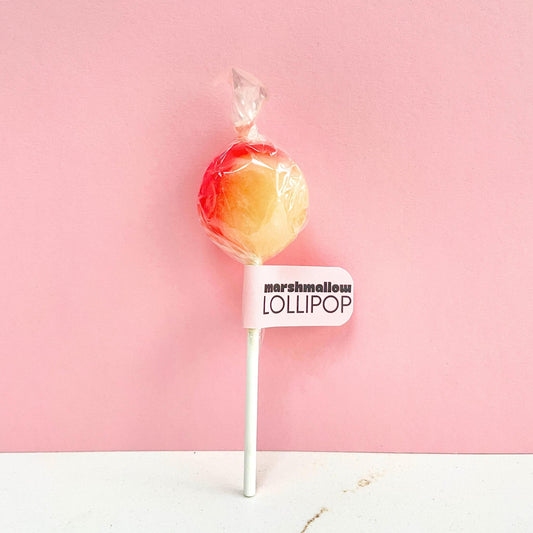 Pink and yellow marshmallow flavoured lollipop on a stick against a pink background