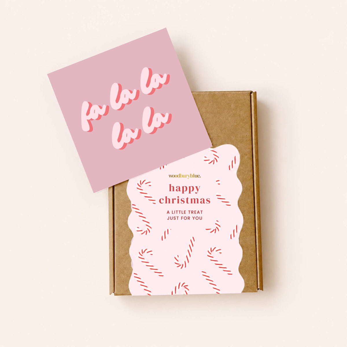 Pink Fa La La Christmas notecard displayed with a kraft Woodbury Blue letterbox gift box decorated with a candy cane Christmas sticker.
