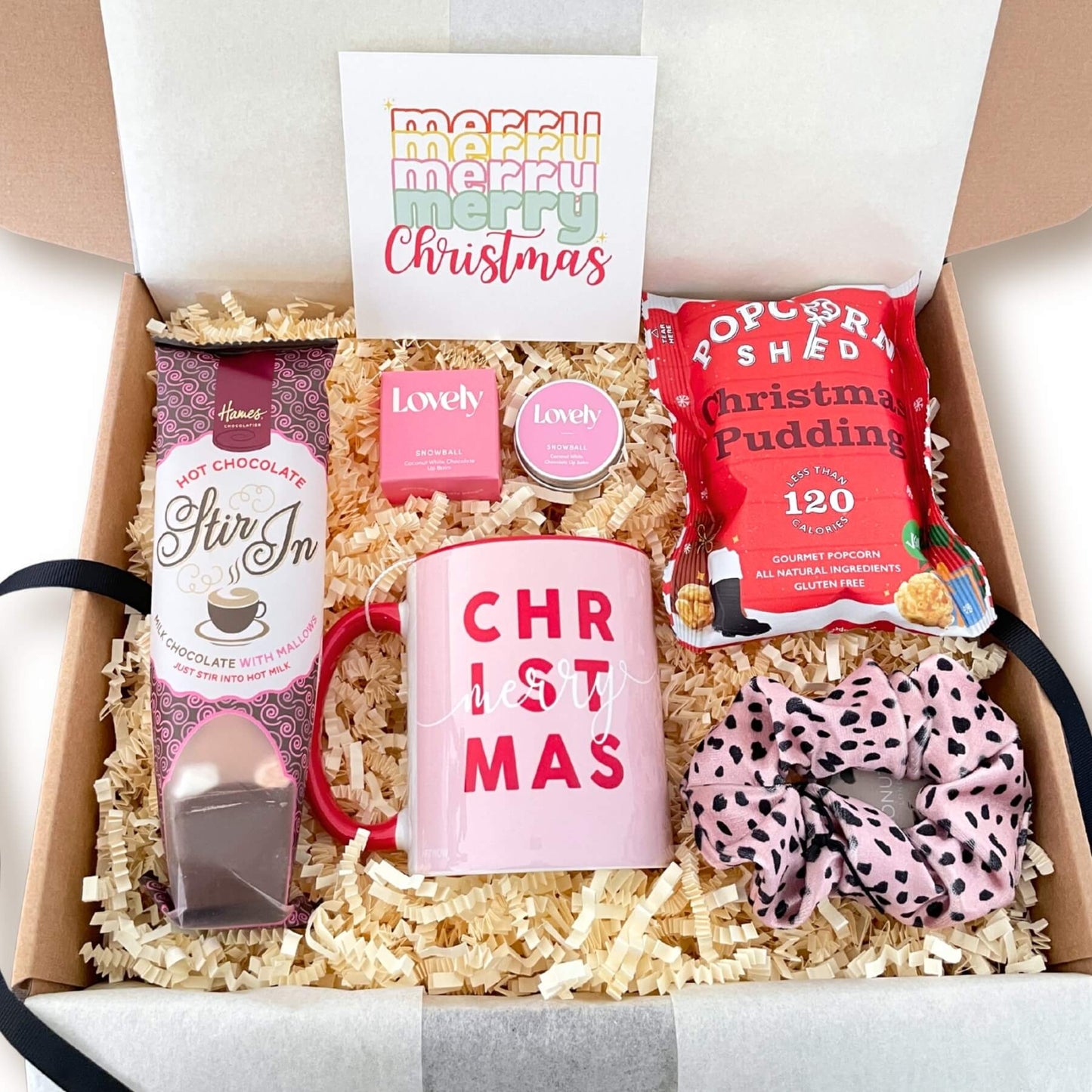 Open Merry Christmas Gift Box showing mug, hot chocolate, popcorn, lip balm, scrunchie and a Christmas notecard.
