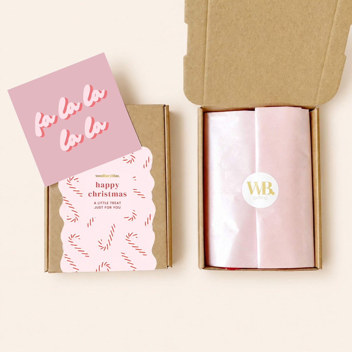 Woodbury Blue Christmas letterbox gift showing pink tissue paper sealed with a WB sticker, alongside the festive gift box and Fa La La notecard.