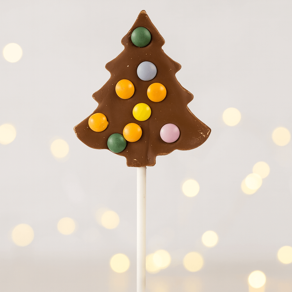 Hames milk chocolate Christmas tree lollipop decorated with colourful candy beans on a stick, festive background with soft fairy lights