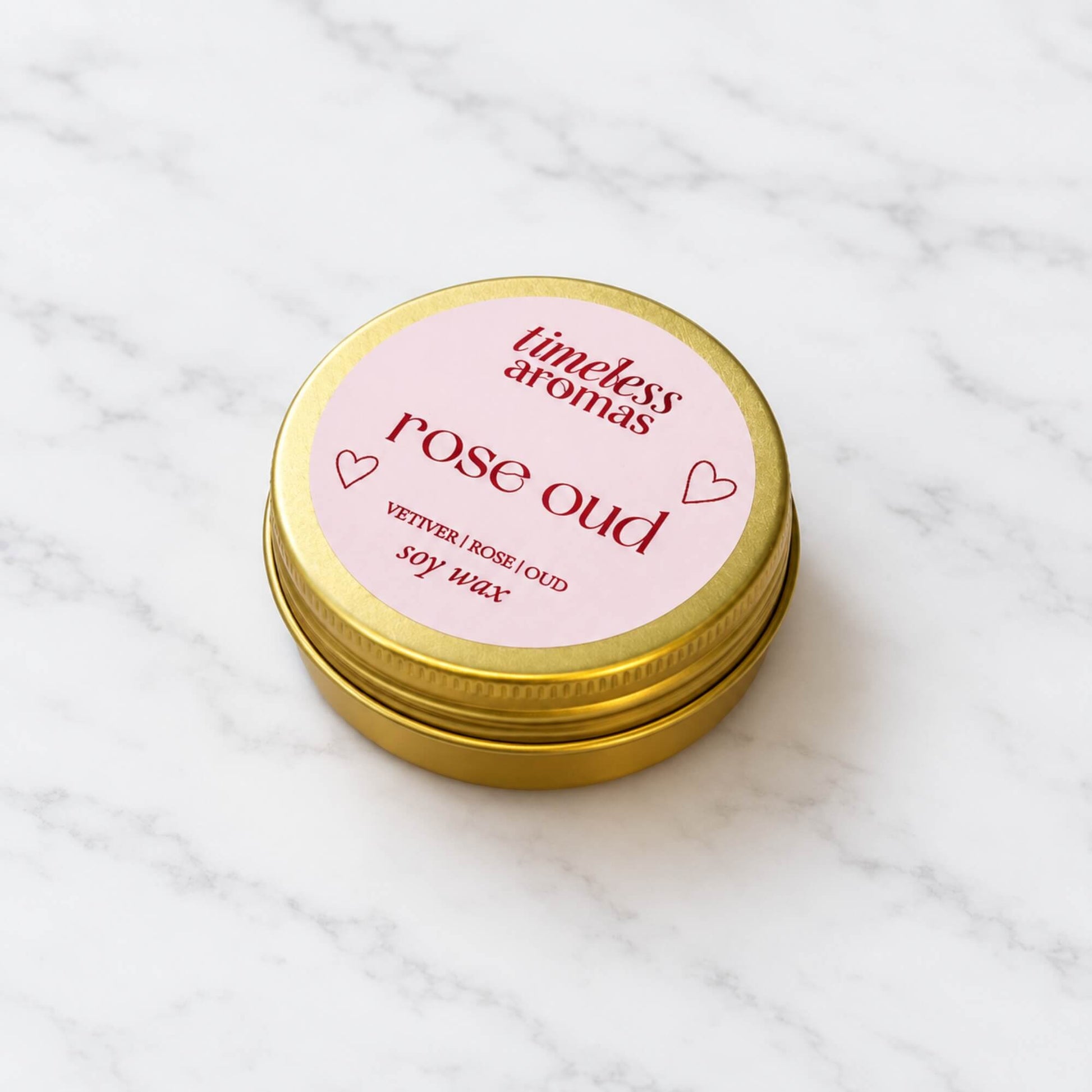 Mini Rose Oud candle in a gold tin with pale pink label and red text