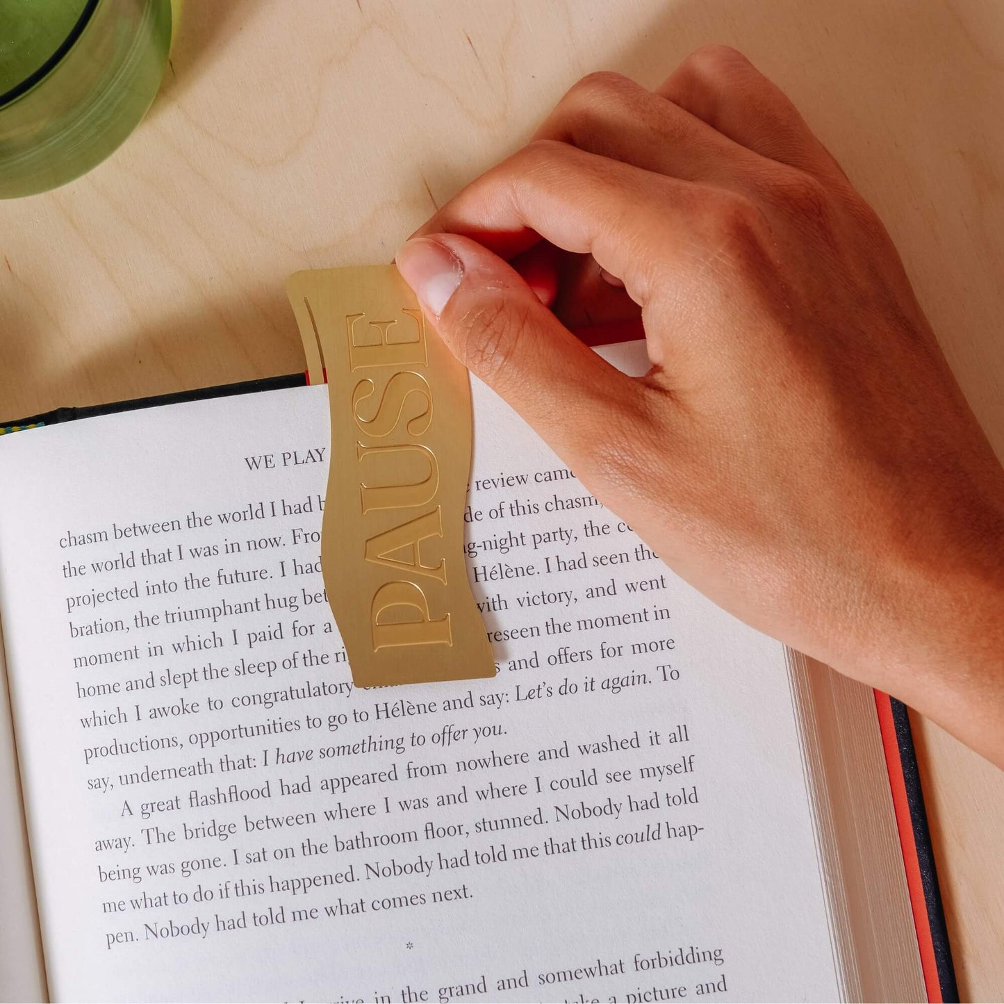 Papier Brass 'Pause' Bookmark marking the page of an open book.