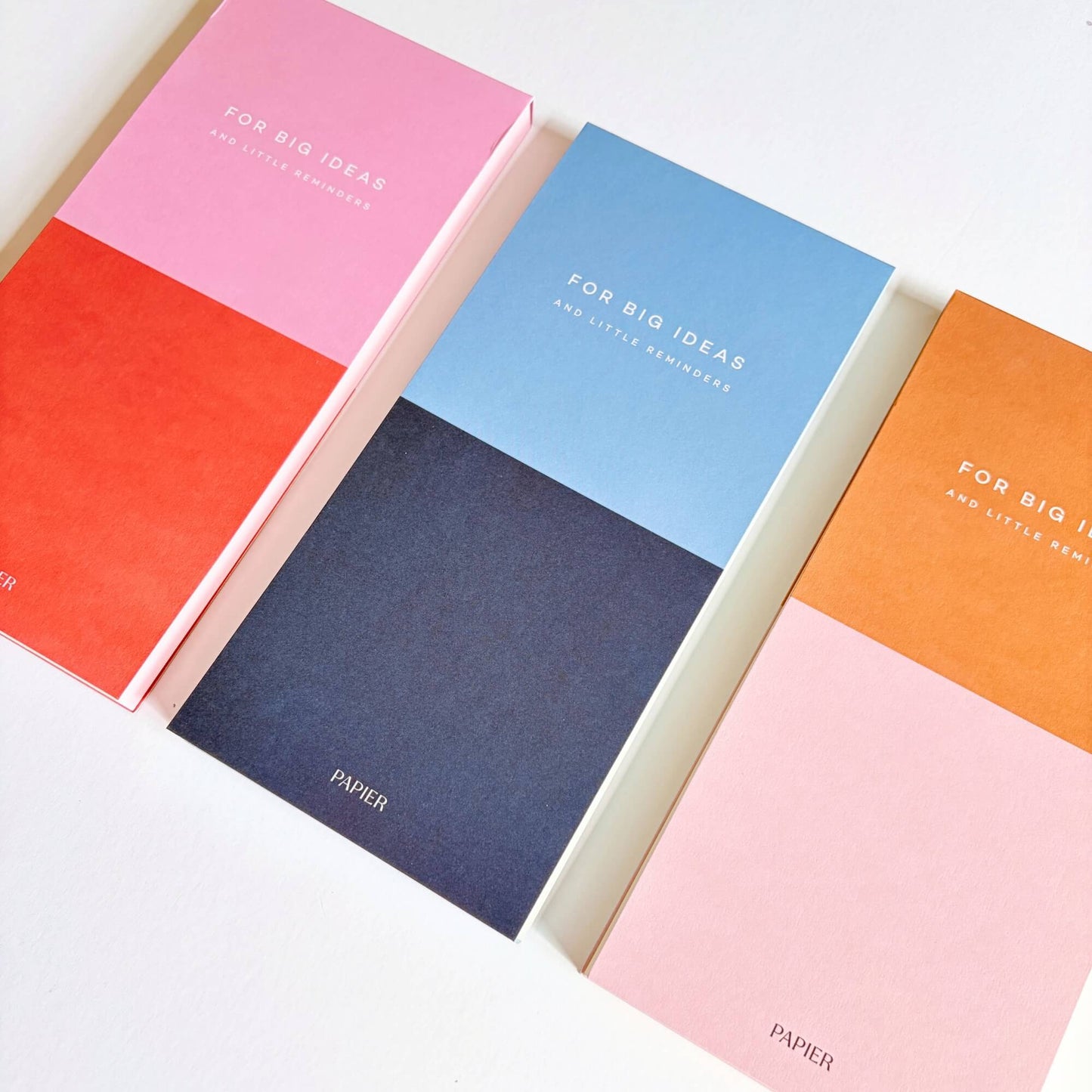 Angled view of three Papier colourblock list notepads in pink, blue and orange colourways.
