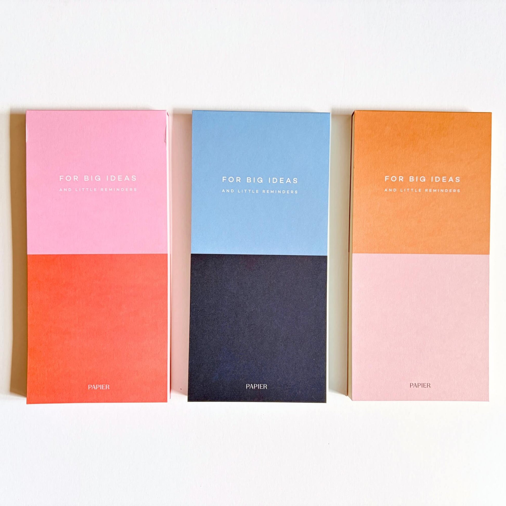 Three Papier colourblock list notepads in pink and red, blue and navy, and orange and pale pink.