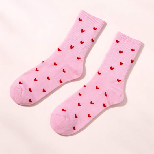 Pink socks with small red heart pattern on a pale pink background