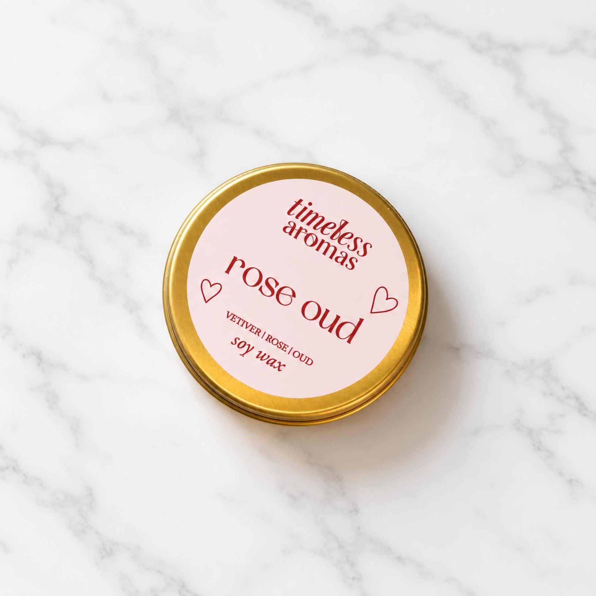 Rose Oud soy wax candle by Timeless Aromas in a mini gold tin on a light marble background
