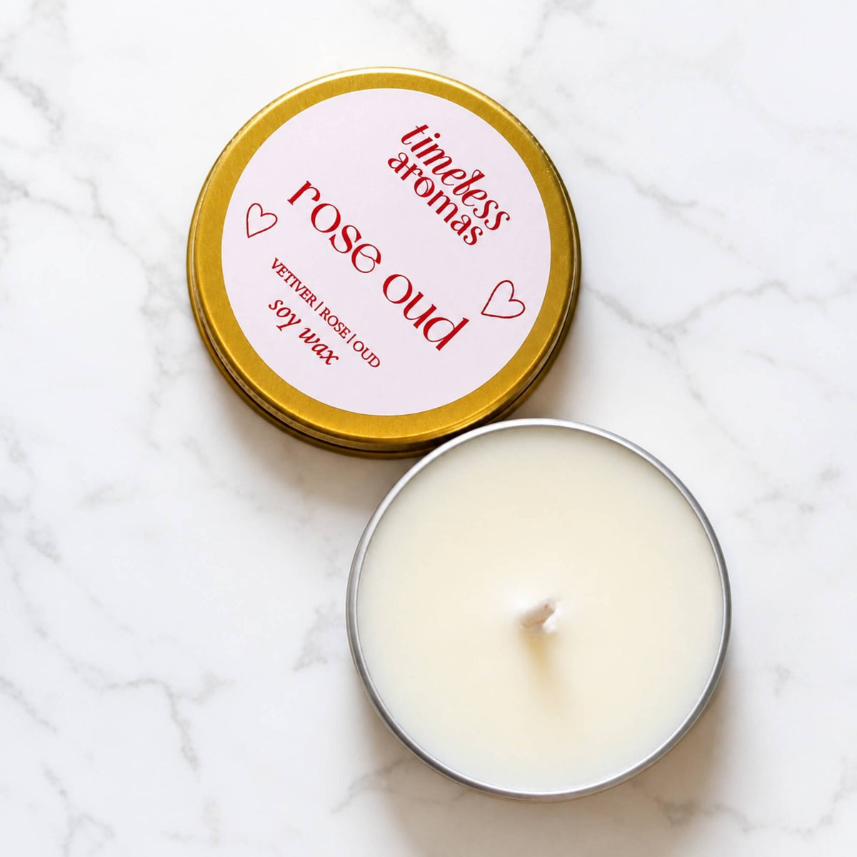 Open Rose Oud soy wax candle in a mini gold tin with labelled lid beside it