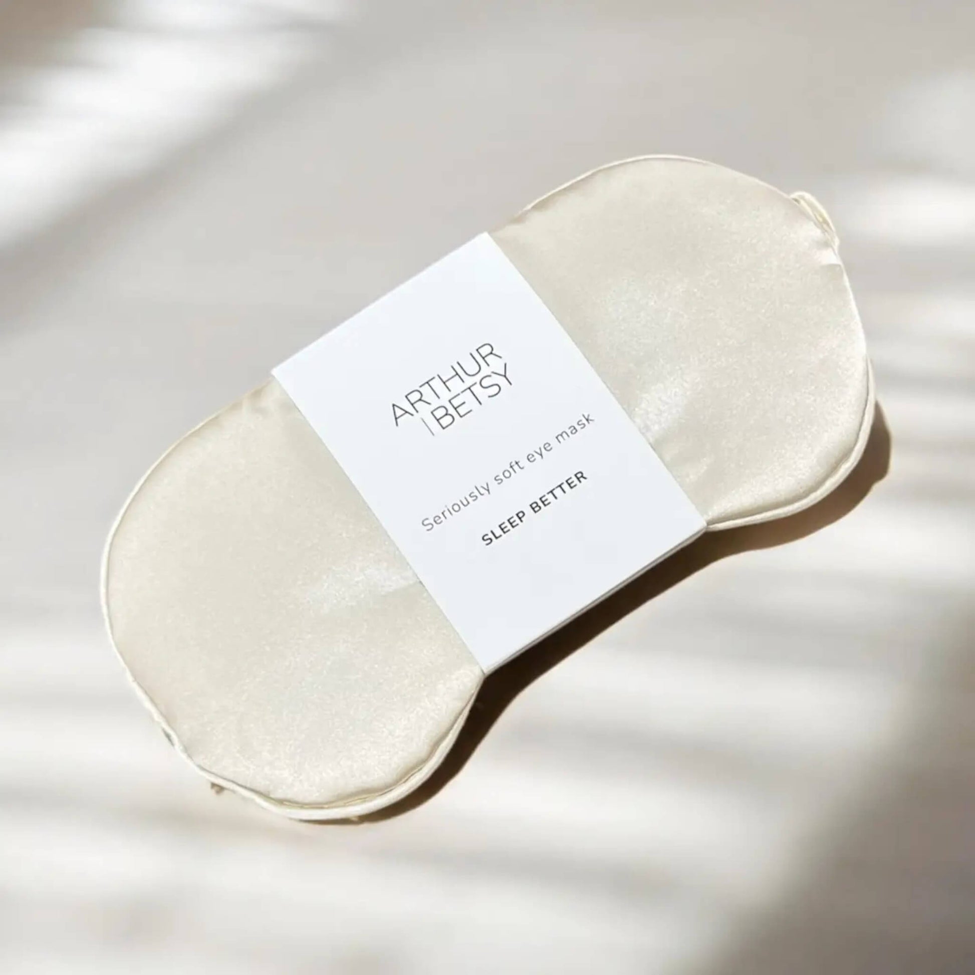 Arthur Betsy satin sleep mask in champagne ivory, front-facing on a neutral background