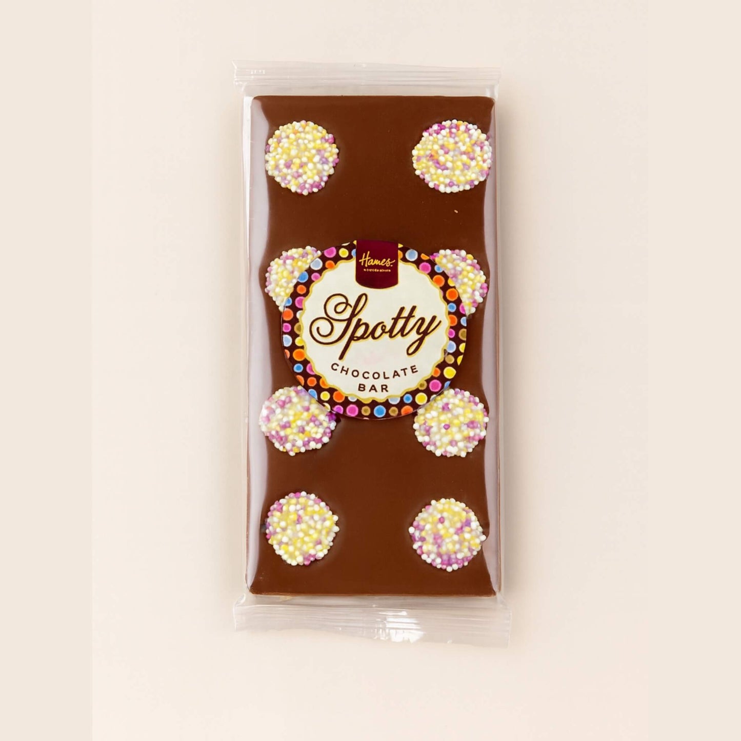 Hames Spotty milk chocolate bar decorated with white chocolate snowies in clear packaging on a light neutral background
