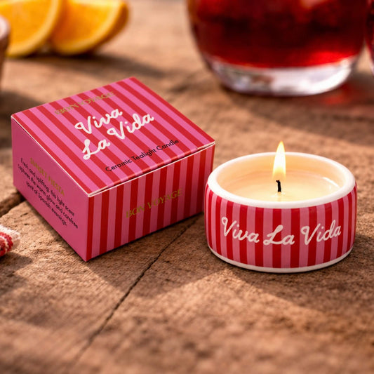Lit Viva La Vida ceramic tealight candle beside its red and pink striped gift box