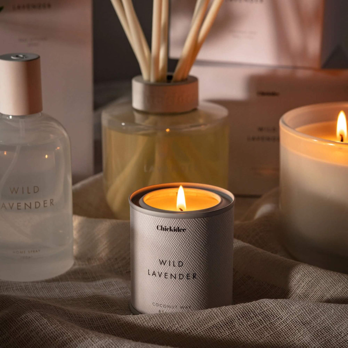 Lit Wild Lavender coconut wax tin candle displayed with matching Chickidee home fragrance products