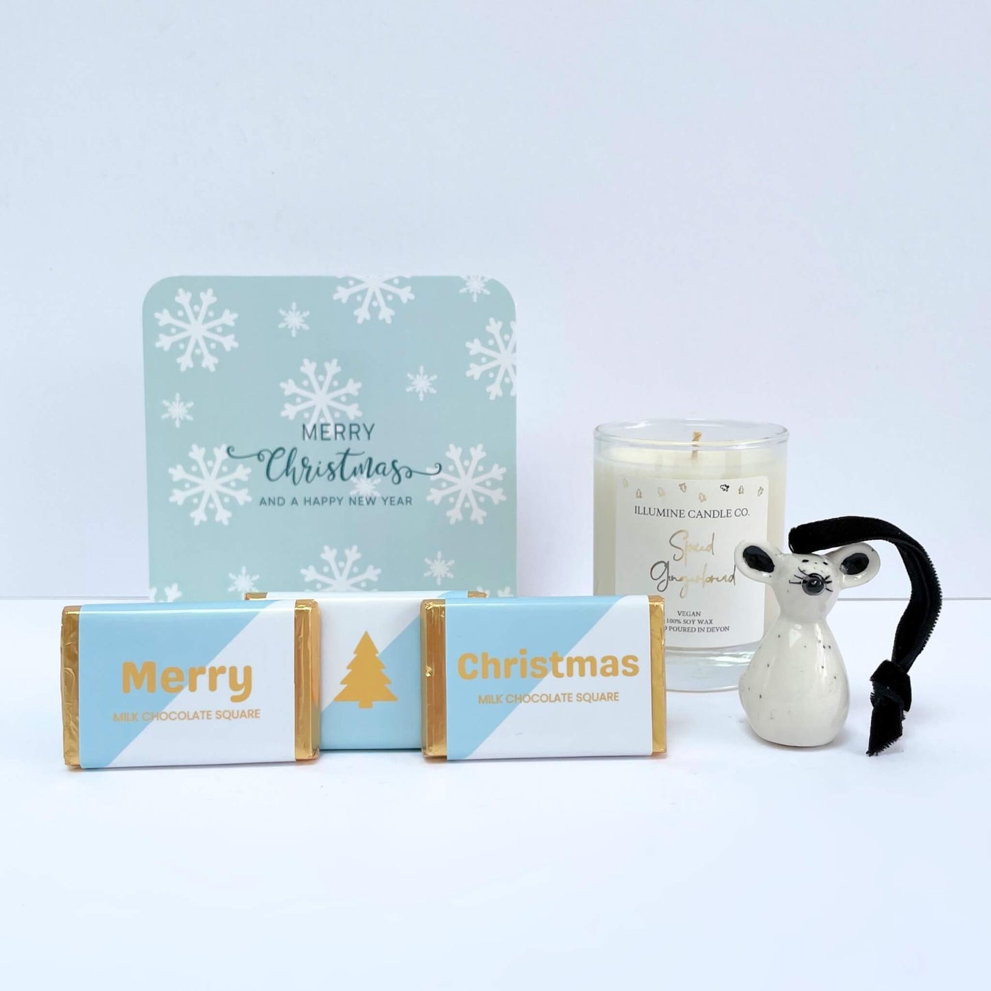 Front view of Winter Glow gift contents: blue snowflake gift box, candle, reindeer, chocolates, and notecard