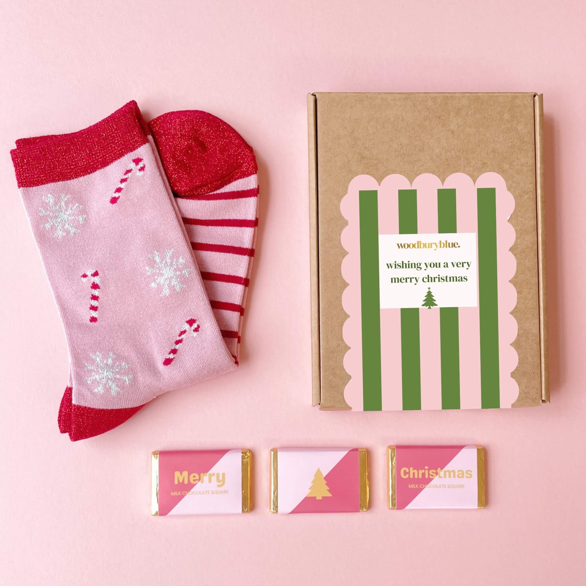 Christmas socks and chocolates gift box on pink background with striped packaging label and bamboo candy cane socks
