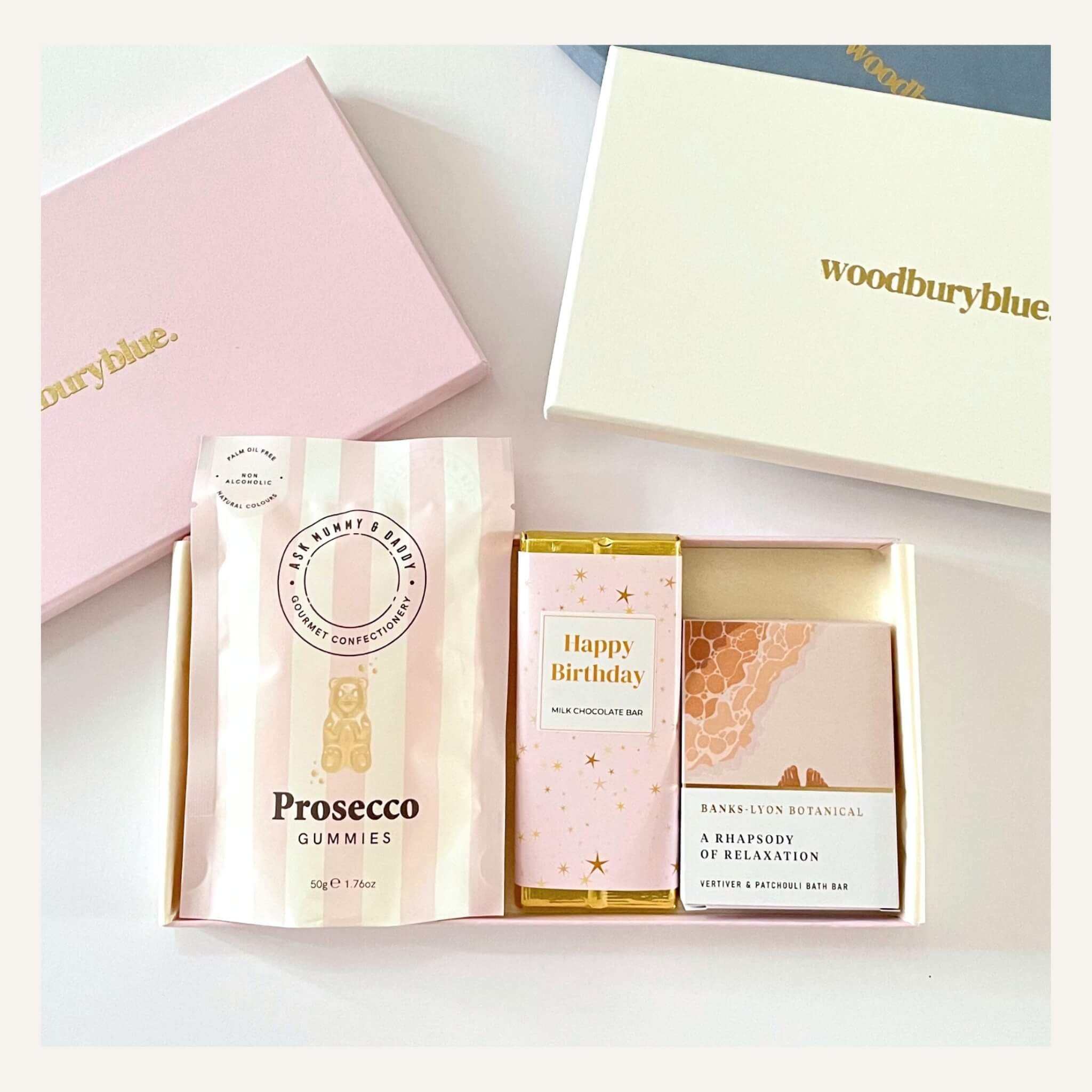 Letterbox gift box from Woodbury Blue with prosecco gummies, birthday chocolate bar, and Banks Lyon Botanical bath oil bar, beautifully packaged in a pastel gift box.