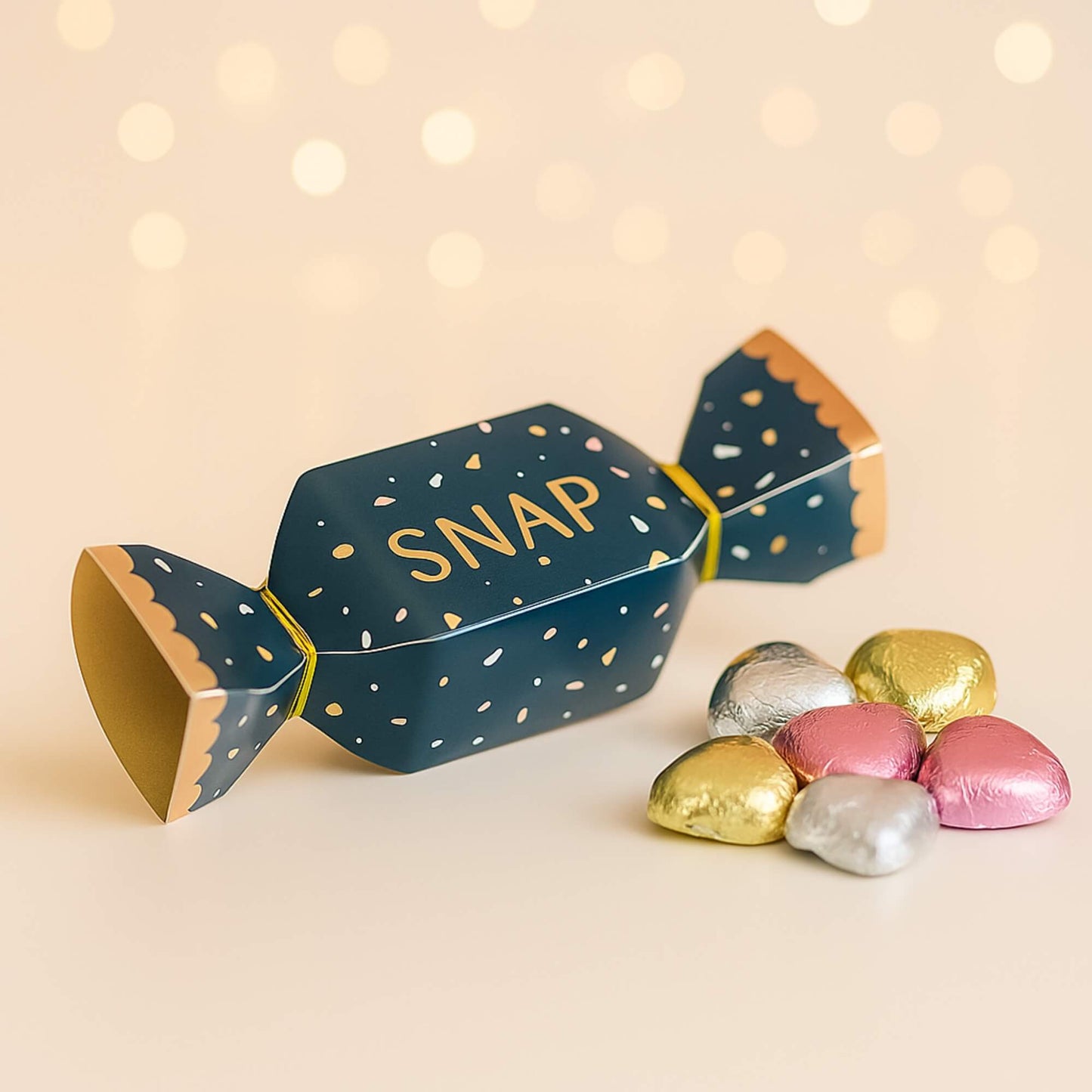 Navy and gold mini Christmas cracker with SNAP design and foil-wrapped milk chocolate hearts by Woodbury Blue, styled on a soft neutral background.