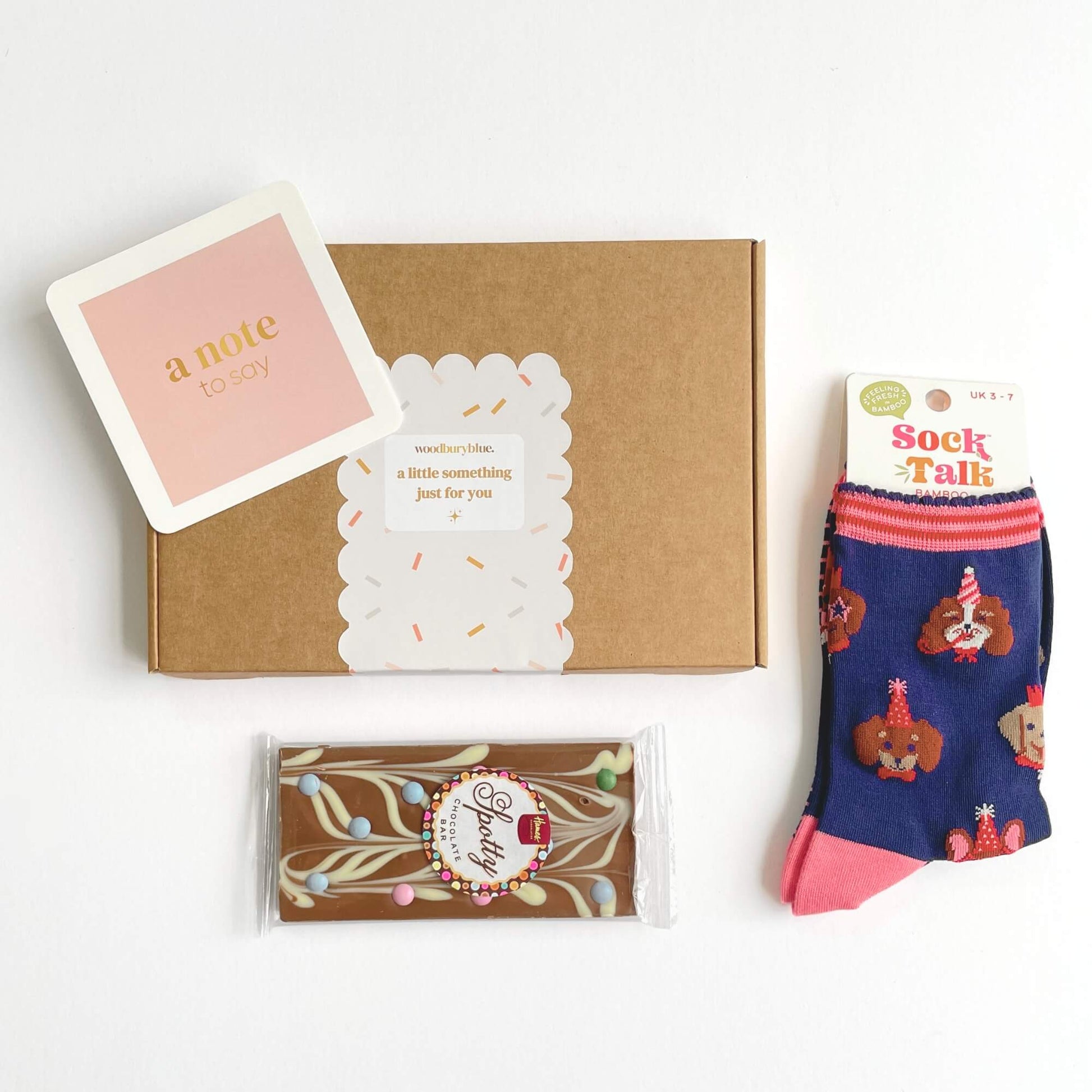 Party Dogs Socks and Chocolates Letterbox Gift laid out flat with chocolate bar, notecard and kraft gift box