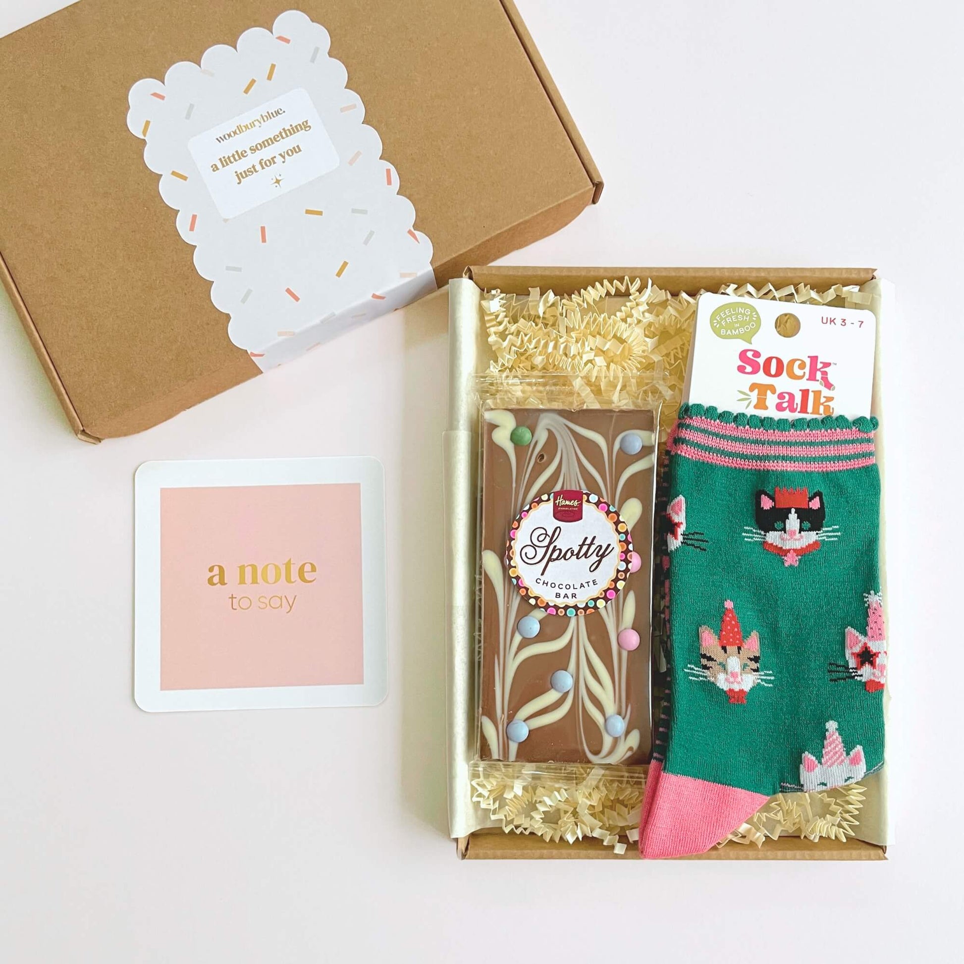 Open Party Cats Socks and Chocolates Letterbox Gift showing chocolate bar, bamboo socks and pink notecard inside kraft gift box