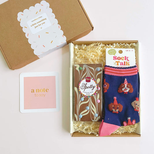 Open Party Dogs Socks and Chocolates Letterbox Gift showing chocolate bar, bamboo socks and pink notecard inside kraft gift box