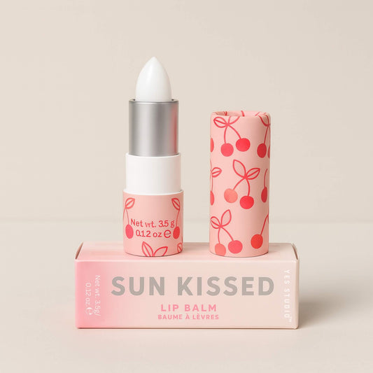 A Sun Kissed lip balm with the cap removed, showing the white balm bullet and cherry patterned pink tube on top of its matching box.
